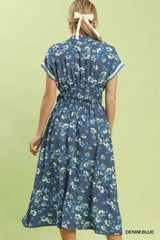 Woman wearing a denim blue floral dress on a light green background