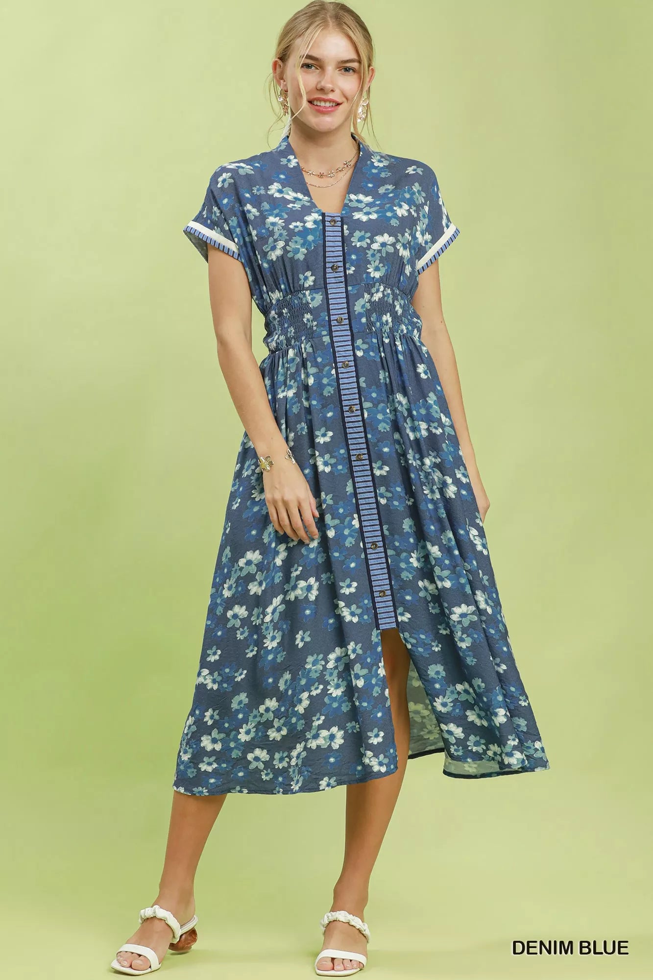 Woman wearing a denim blue floral dress on a light green background