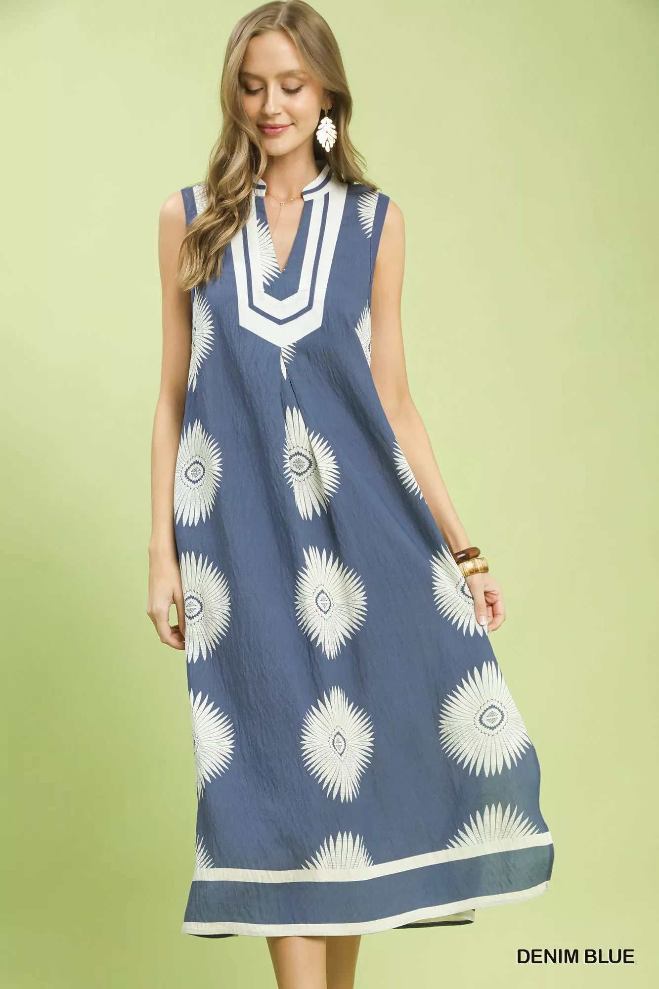 Woman wearing a denim blue dress with white floral patterns on a light green background