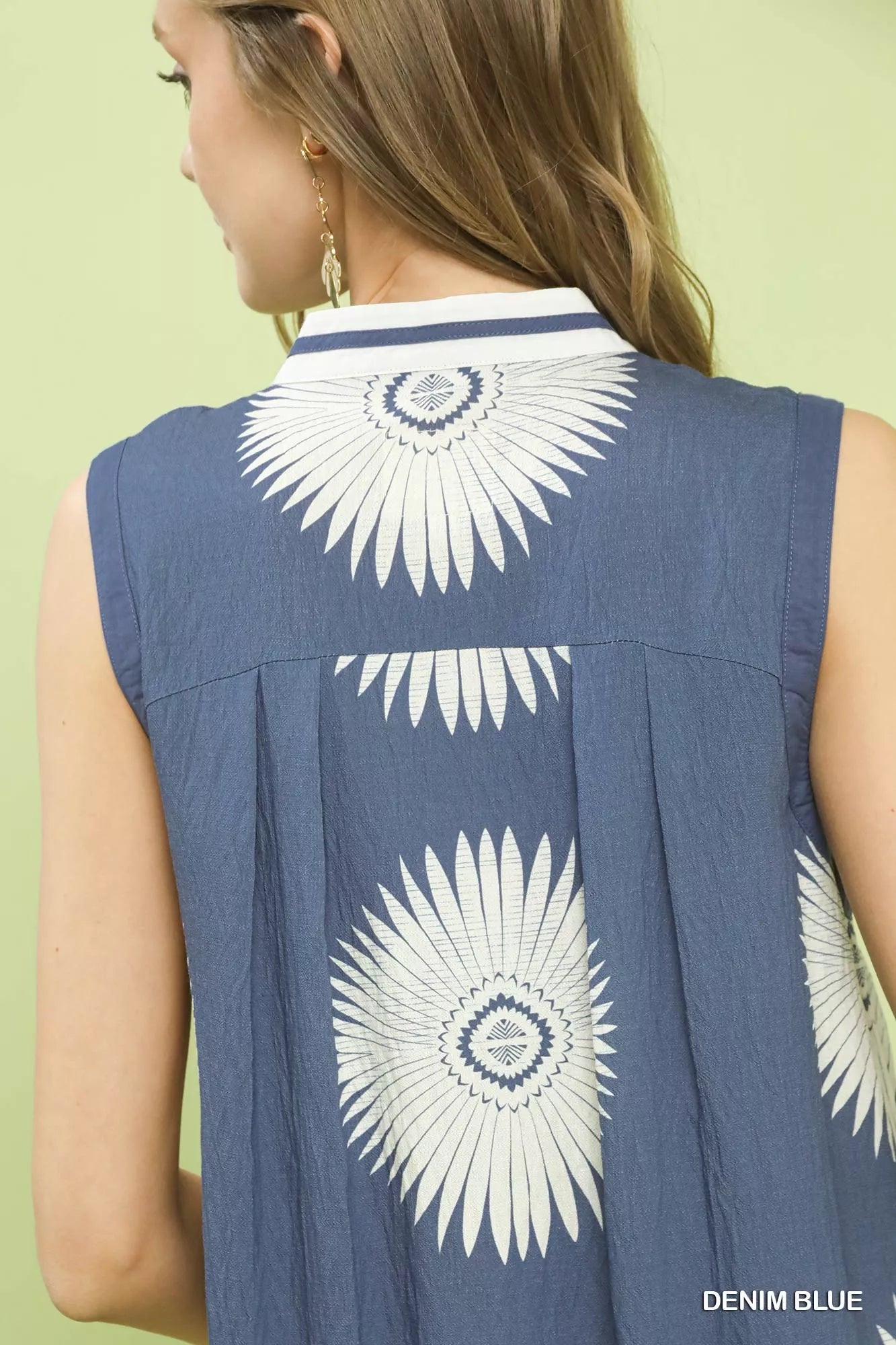Blue sleeveless top with white floral patterns on a light green background