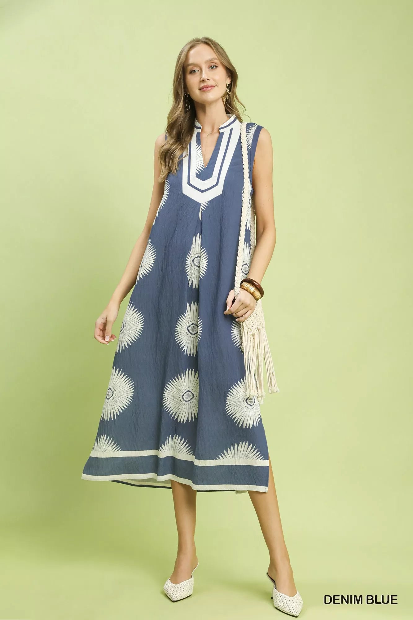 Woman wearing a denim blue dress with white patterns on a light green background