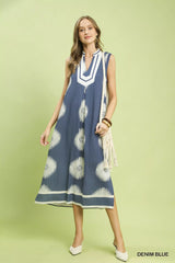 Woman wearing a denim blue dress with white patterns on a light green background