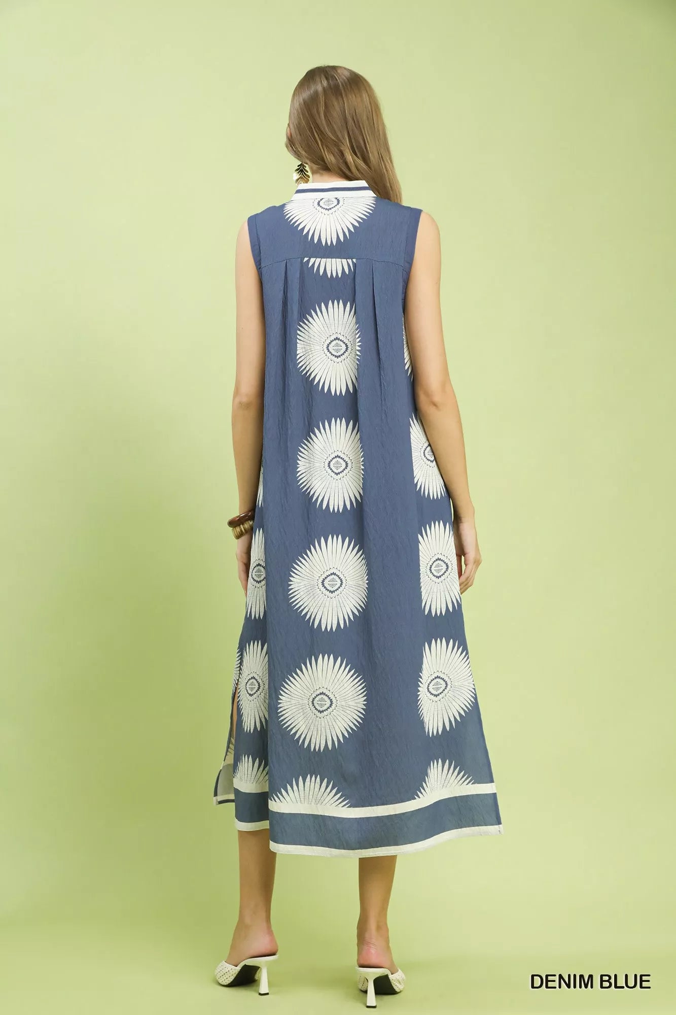 Woman wearing a denim blue dress with white floral patterns on a light green background