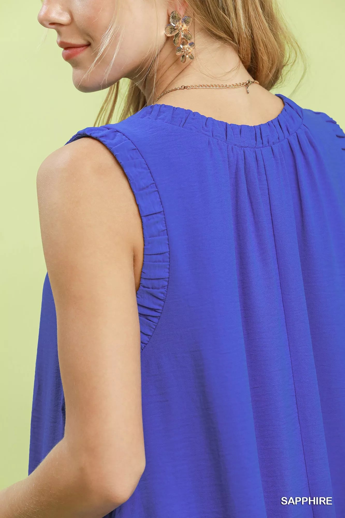 Woman wearing a blue sleeveless top against a light green background