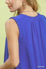 Woman wearing a blue sleeveless top against a light green background