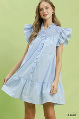 Woman wearing a light blue dress with ruffled sleeves on a green background