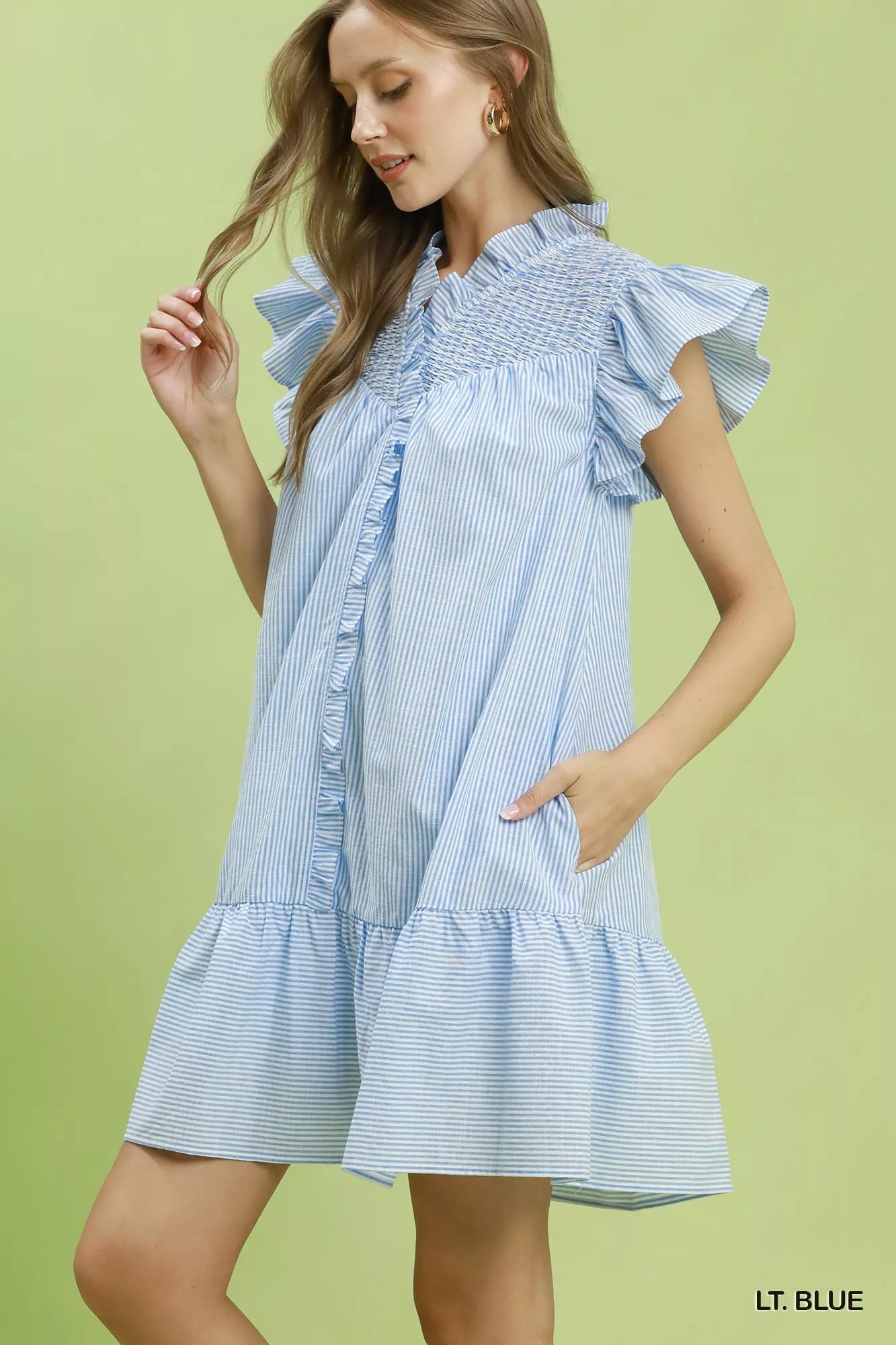 Woman wearing a light blue striped dress against a green background
