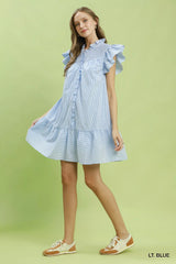 Woman wearing a light blue dress with ruffled sleeves on a green background