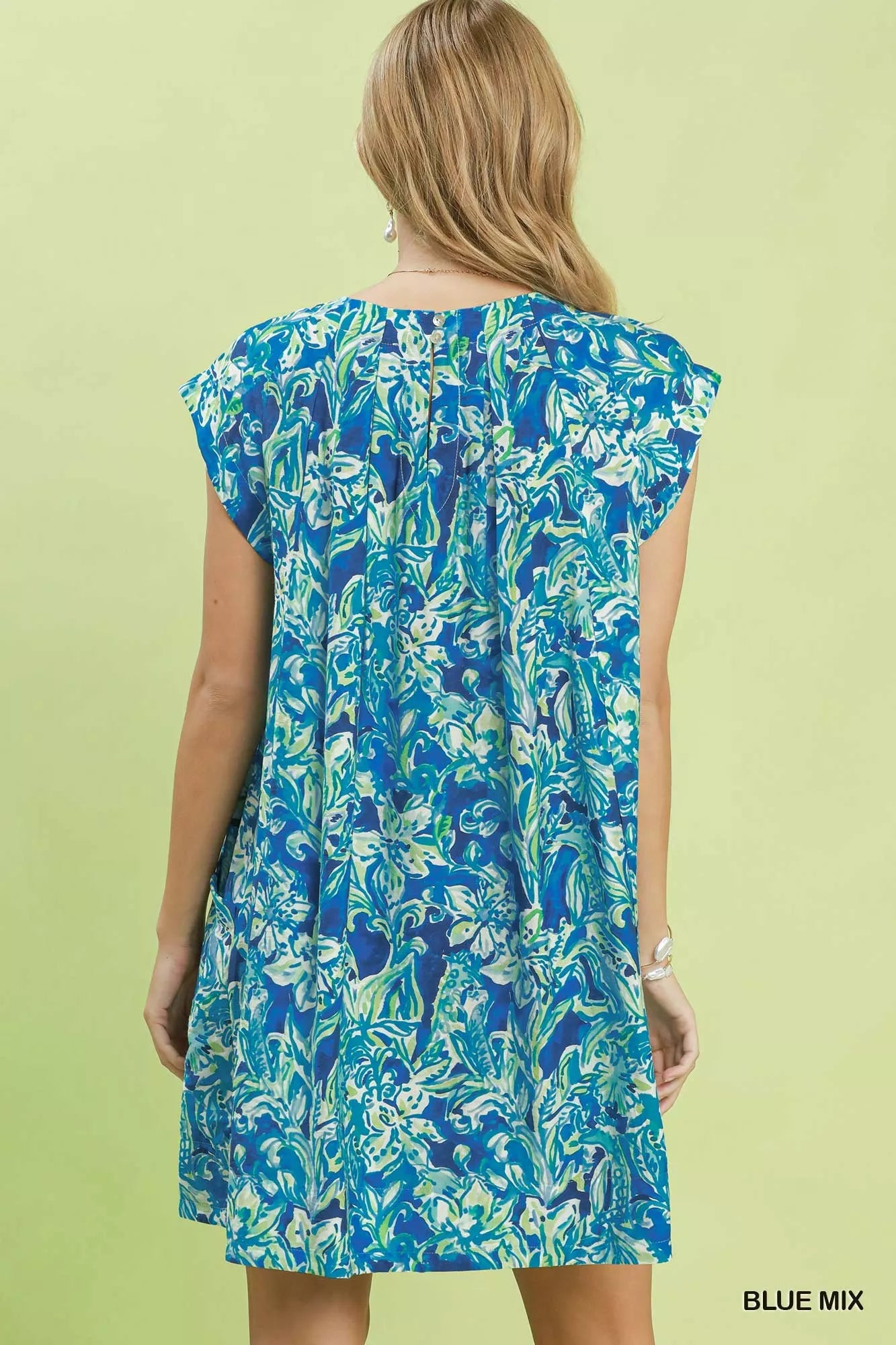 Woman wearing a blue floral dress against a light green background