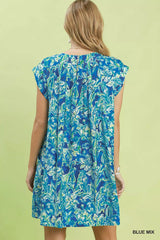 Woman wearing a blue floral dress against a light green background