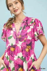 Woman wearing a vibrant floral dress against a light blue background