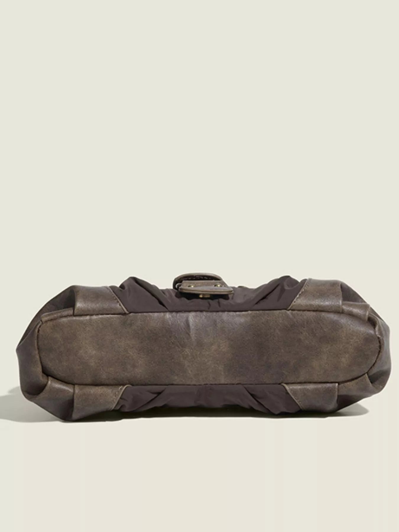Brown leather duffel bag on a beige background