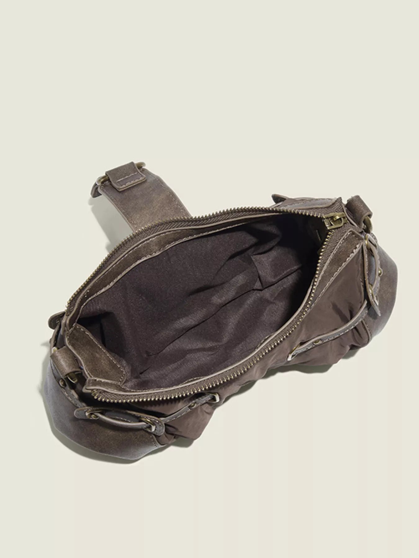 Brown leather bag with a zipper on a beige background