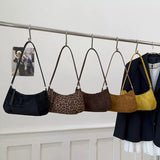 Suede vintage-style shoulder bag with a minimalist silhouette paired with a neutral outfit.
