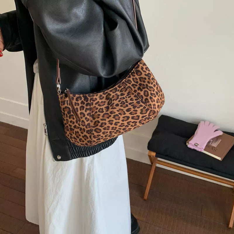 Leopard suede vintage-style shoulder bag with a minimalist silhouette paired with a neutral outfit.