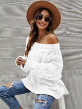 Woman wearing a white cable knit openwork off-shoulder sweater with distressed jeans and a wide-brim hat.