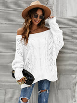 Woman wearing a white cable knit openwork off-shoulder sweater with distressed jeans and a wide-brim hat.