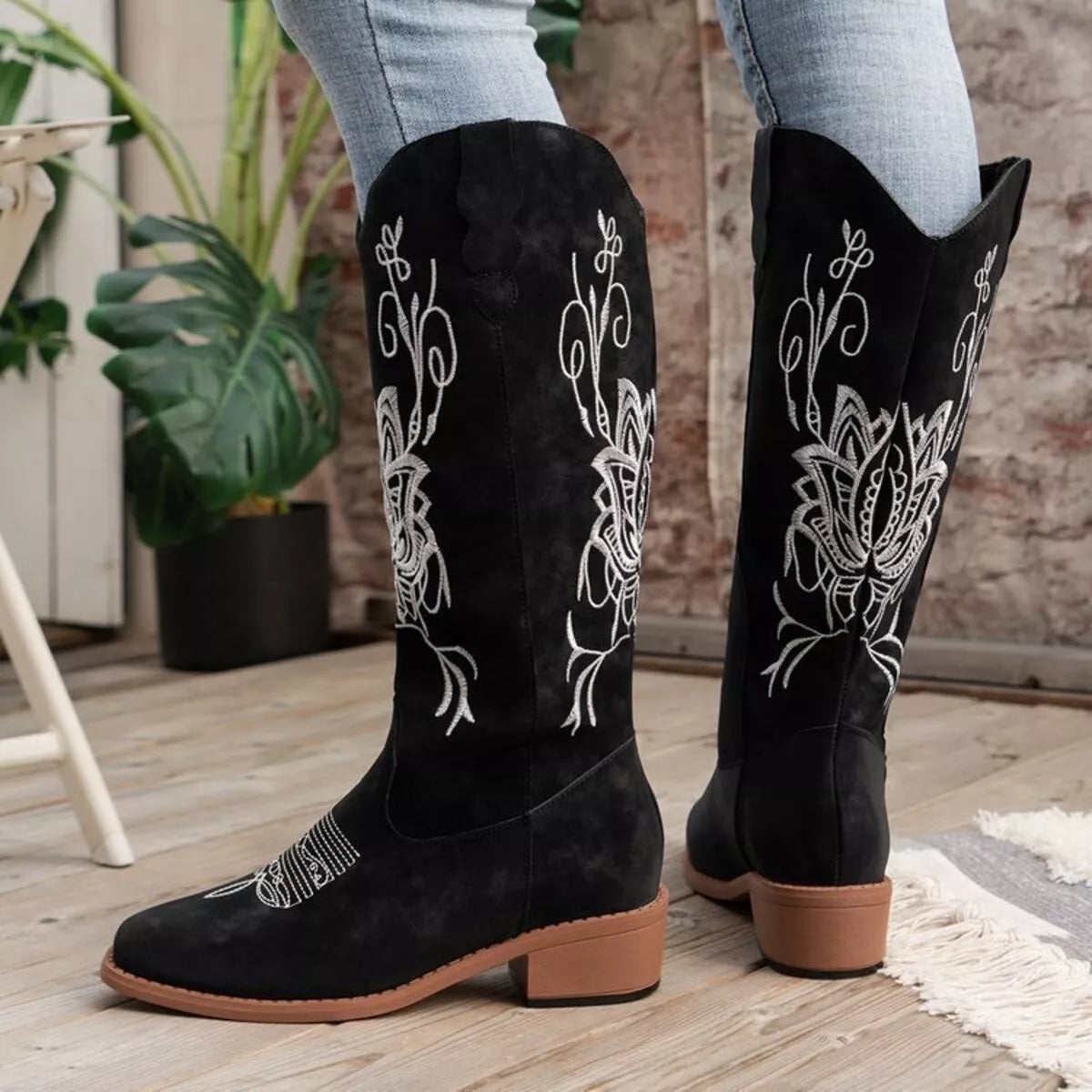 Women’s black Western cowboy boots with white embroidered detailing and mid-height block heels.