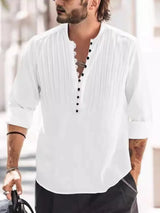 Man wearing a white button-detail long sleeve cotton polo with rolled sleeves and black pants.