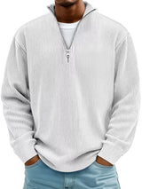 Man wearing a white ribbed corduroy quarter zip pullover sweatshirt layered over a white shirt.