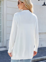 Woman wearing a white open front cardigan with blue jeans, layered over a white tank top for a casual everyday outfit.
