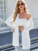 Woman wearing a white open front cardigan with blue jeans, layered over a white tank top for a casual everyday outfit.