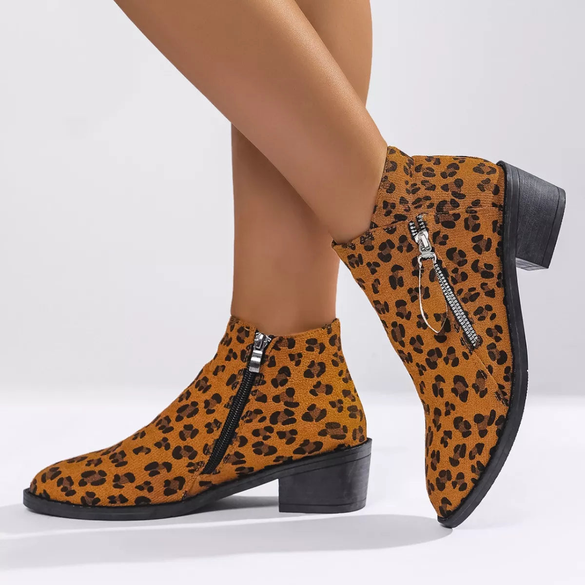 Woman wearing yellow leopard-print ankle boots with block heels and side zipper details.