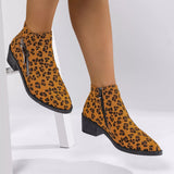 Woman wearing yellow leopard-print ankle boots with block heels and side zipper details.