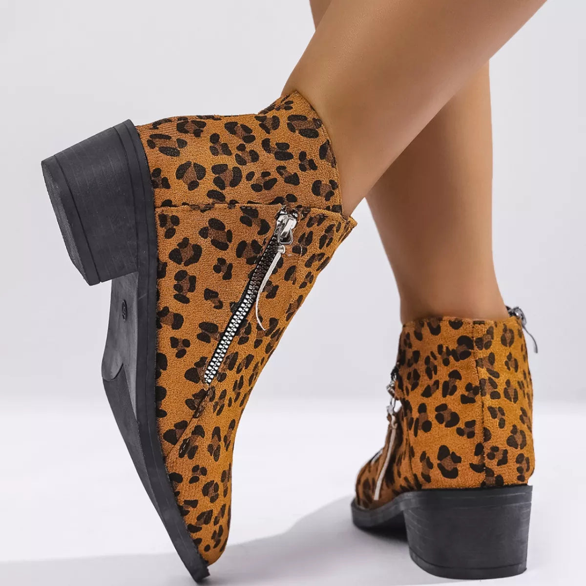 Woman wearing yellow leopard-print ankle boots with block heels and side zipper details.