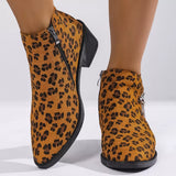 Woman wearing yellow leopard-print ankle boots with block heels and side zipper details.