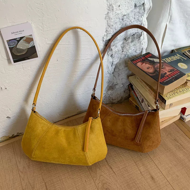 Yellow and Caramel suede vintage-style shoulder bag with a minimalist silhouette paired with a neutral outfit.