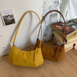 Yellow and Caramel suede vintage-style shoulder bag with a minimalist silhouette paired with a neutral outfit.